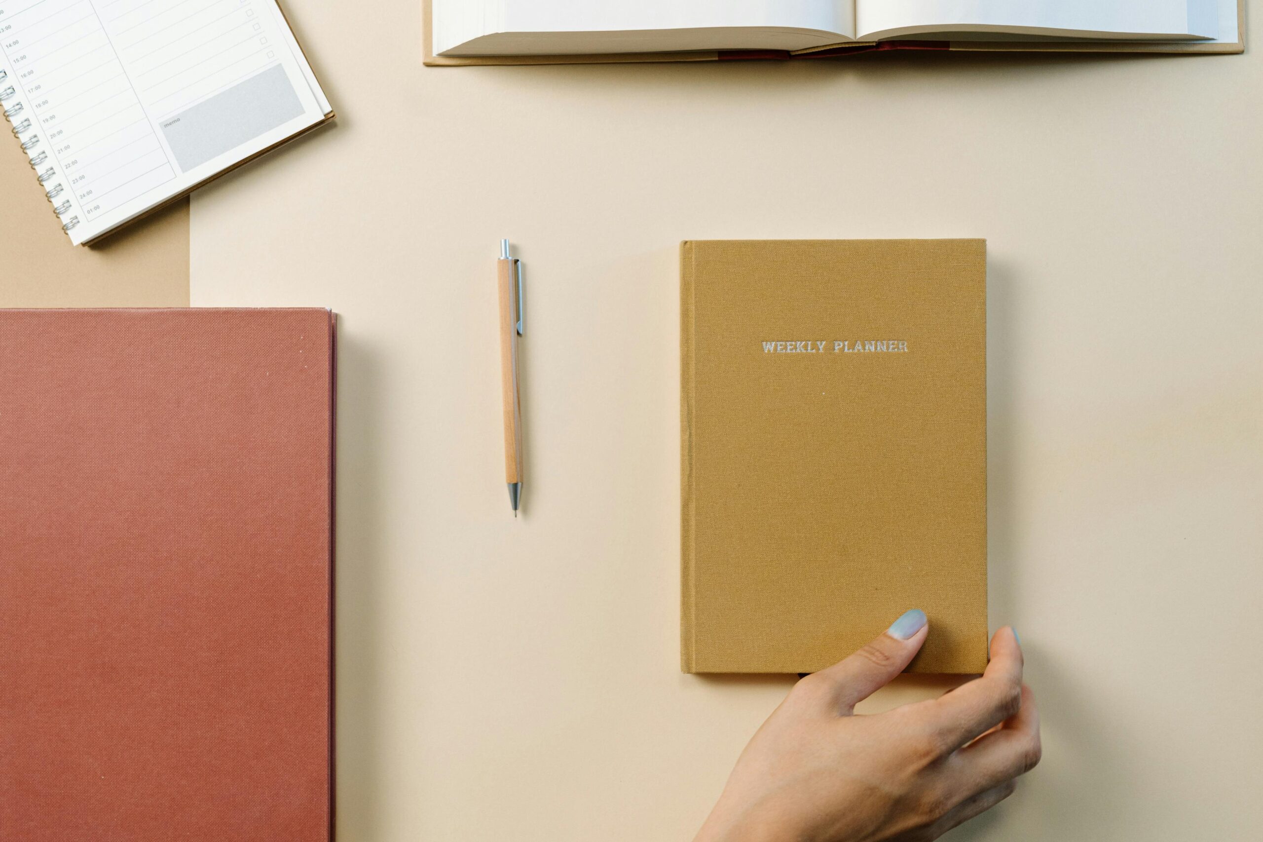 Top-down view of a desk with a weekly planner, notebook, and pen promoting organization.